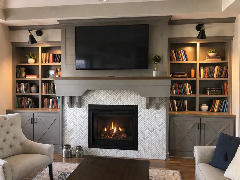 Living room fireplace wall with angled books, herringbone fireplace surround, mantel brackets, and X cabinet doors